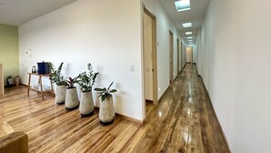 A hallway with wooden flooring, white walls, and multiple potted plants. - Casa Hotel Real (Circasia)
