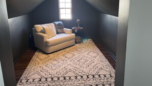 Een gezellig zolderkamer met een witte bank, een vloerkleed met dessin en een klein bijzettafeltje met een wereldbol.