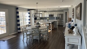 Een moderne keuken met witte kasten, een centraal eiland en een eethoek met een ronde tafel en stoelen.