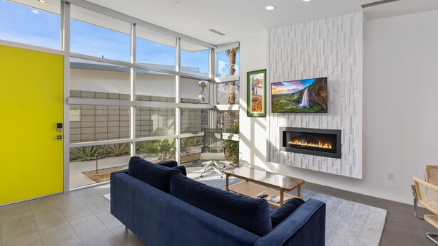 A modern living room with a large window, a fireplace, and a TV mounted on the wall. - Come visit Palm Springs! (Palm Springs)