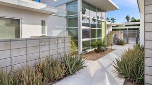 A modern building with large glass windows, a concrete pathway, and various plants. - Come visit Palm Springs! (Palm Springs)
