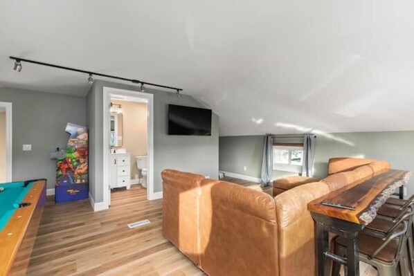 A compact living space with a pool table, a leather sofa, and a wooden coffee table.