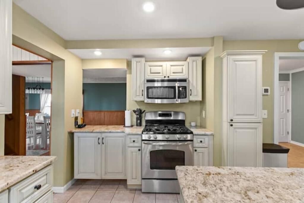 A kitchen with white cabinets, a stainless steel stove, and a microwave.