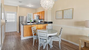 A kitchen with wooden cabinets, a stainless steel refrigerator, a microwave, and a chandelier.