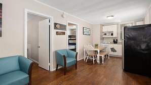 Un espacio habitable compacto con comedor, kitchenette y un sofá azul.