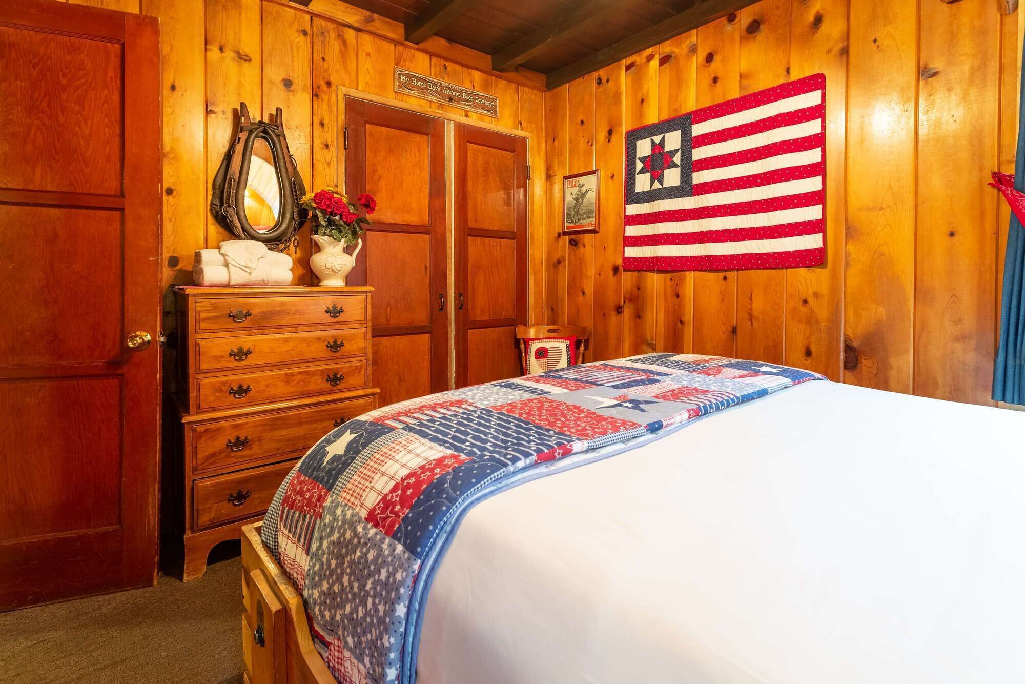 Een houten kamer met een bed, een kaptafel en een Amerikaanse vlag.