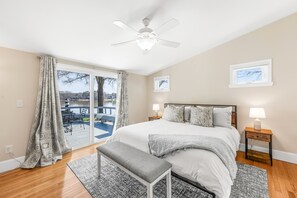 Relax in this serene bedroom with a large bed, ceiling fan, and comfortable seating area outside.