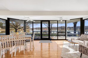 Enjoy a spacious interior with a large window offering a view of the lake and surrounding landscape, a dining area, and a comfortable seating area with a sofa.