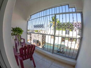 A balcony with a view of a residential area, a chair, and a potted plant.
