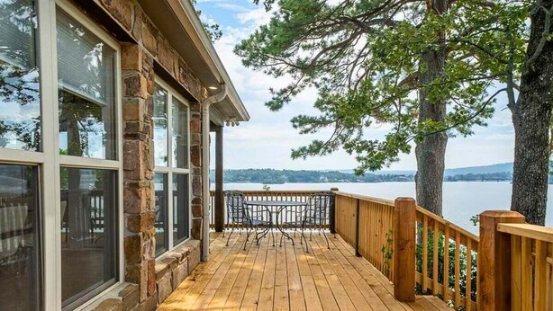 A wooden deck with a railing, large windows, and a view of a lake. - Lakeside | Hot Tub | Private Dock | Views (Hot Springs)