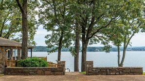 A stone building with a deck, a stone wall, and a view of a lake. - Lakeside | Hot Tub | Private Dock | Views (Hot Springs)