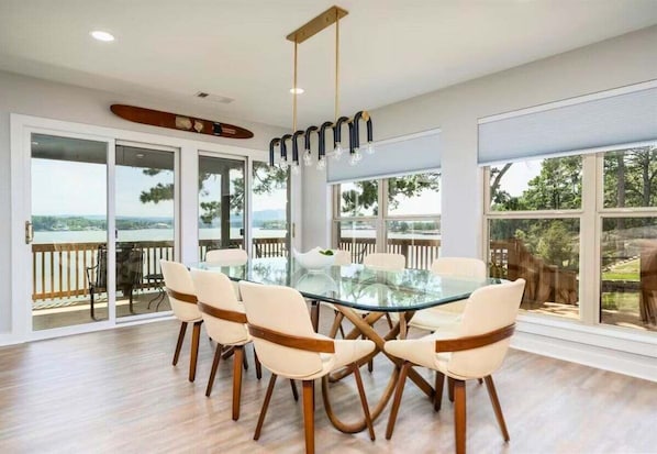 A dining area with a glass table, white chairs, and a view of the outdoors.