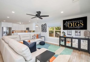 A modern living room with a sofa, a coffee table, and a dining area with a black cabinet.