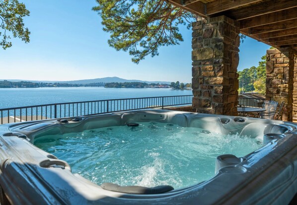 A hot tub with a view of a lake and mountains in the background.