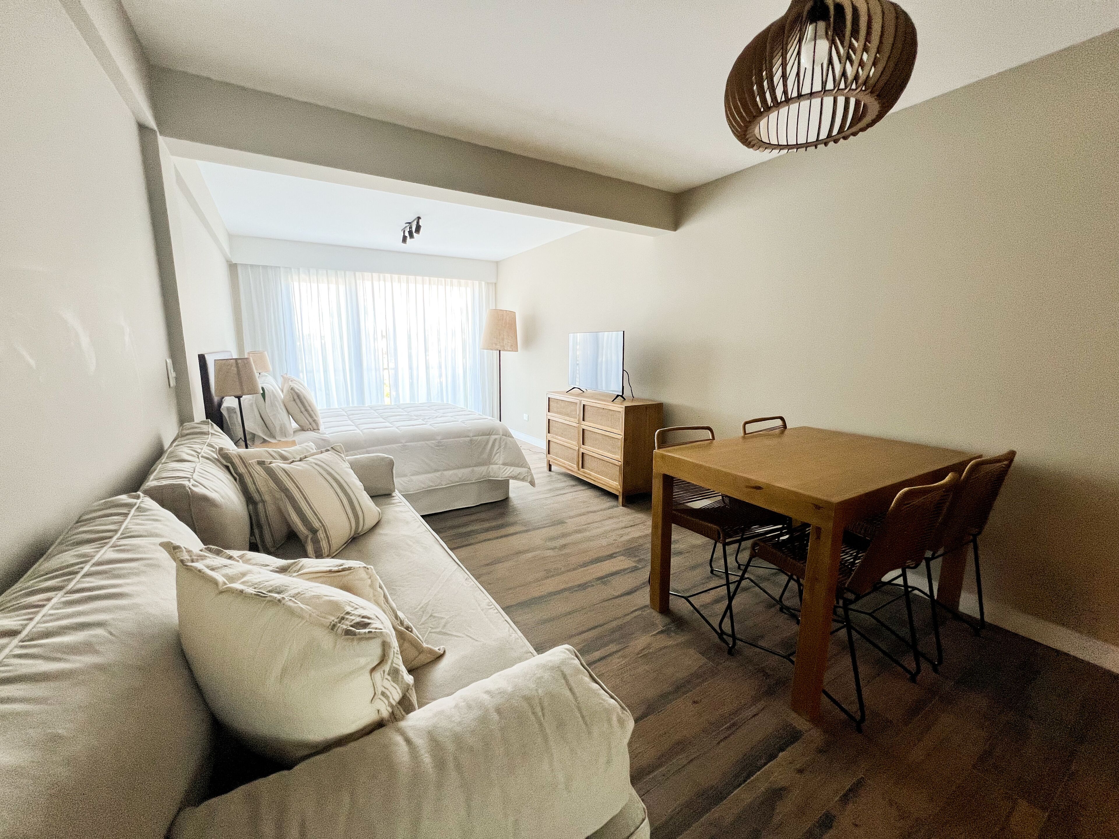 A modern living room with a sofa, a wooden dining table, and a lamp.