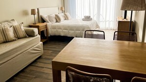 Ein Hotelzimmer mit Bett, Sofa, Esstisch und Lampe.