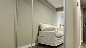 Ein Schlafzimmer mit Schiebetür, einem Bett mit weißer Bettwäsche und Holzboden.