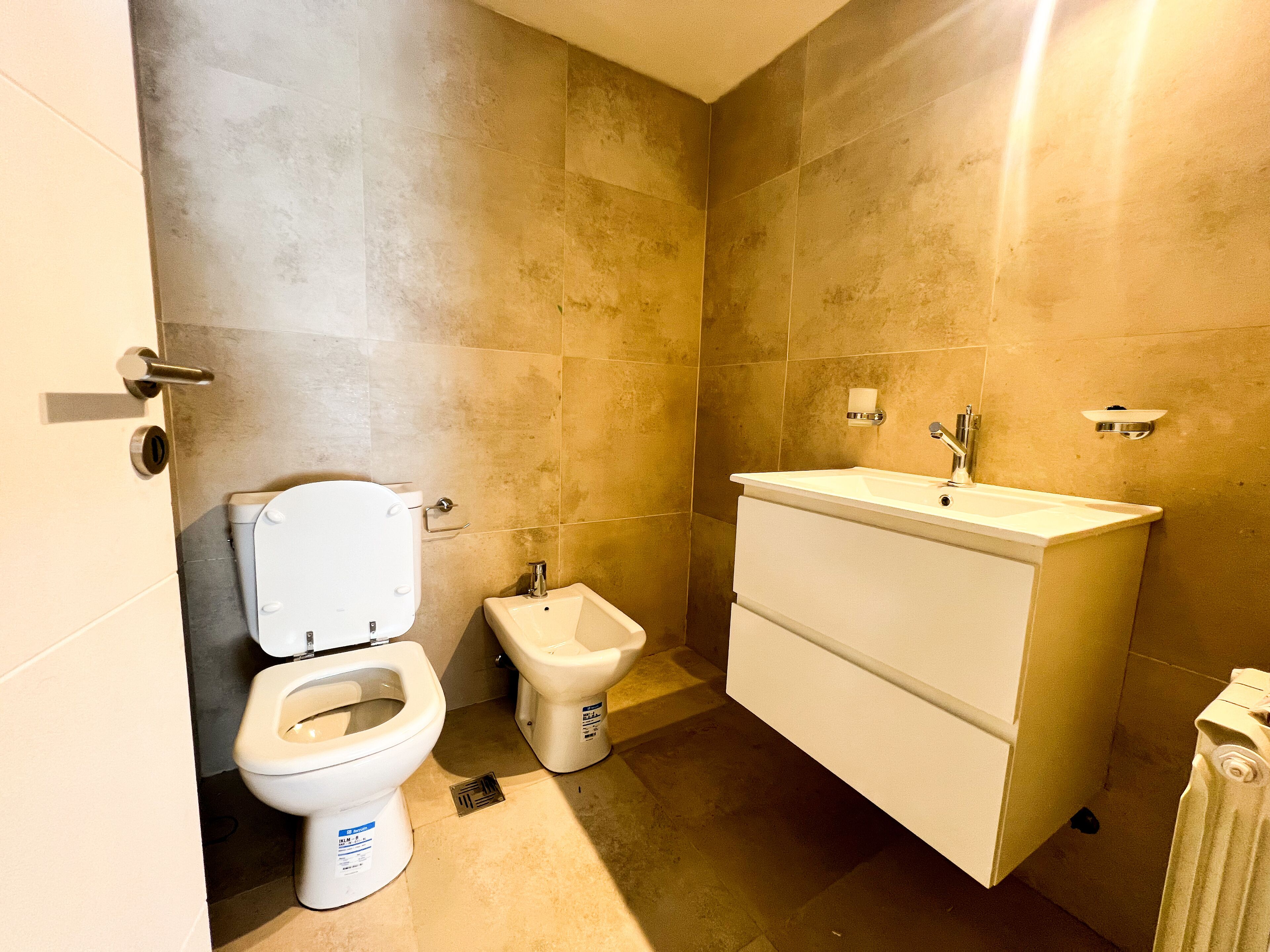 Une salle de bain équipée de toilettes, d’un bidet et d’un lavabo.