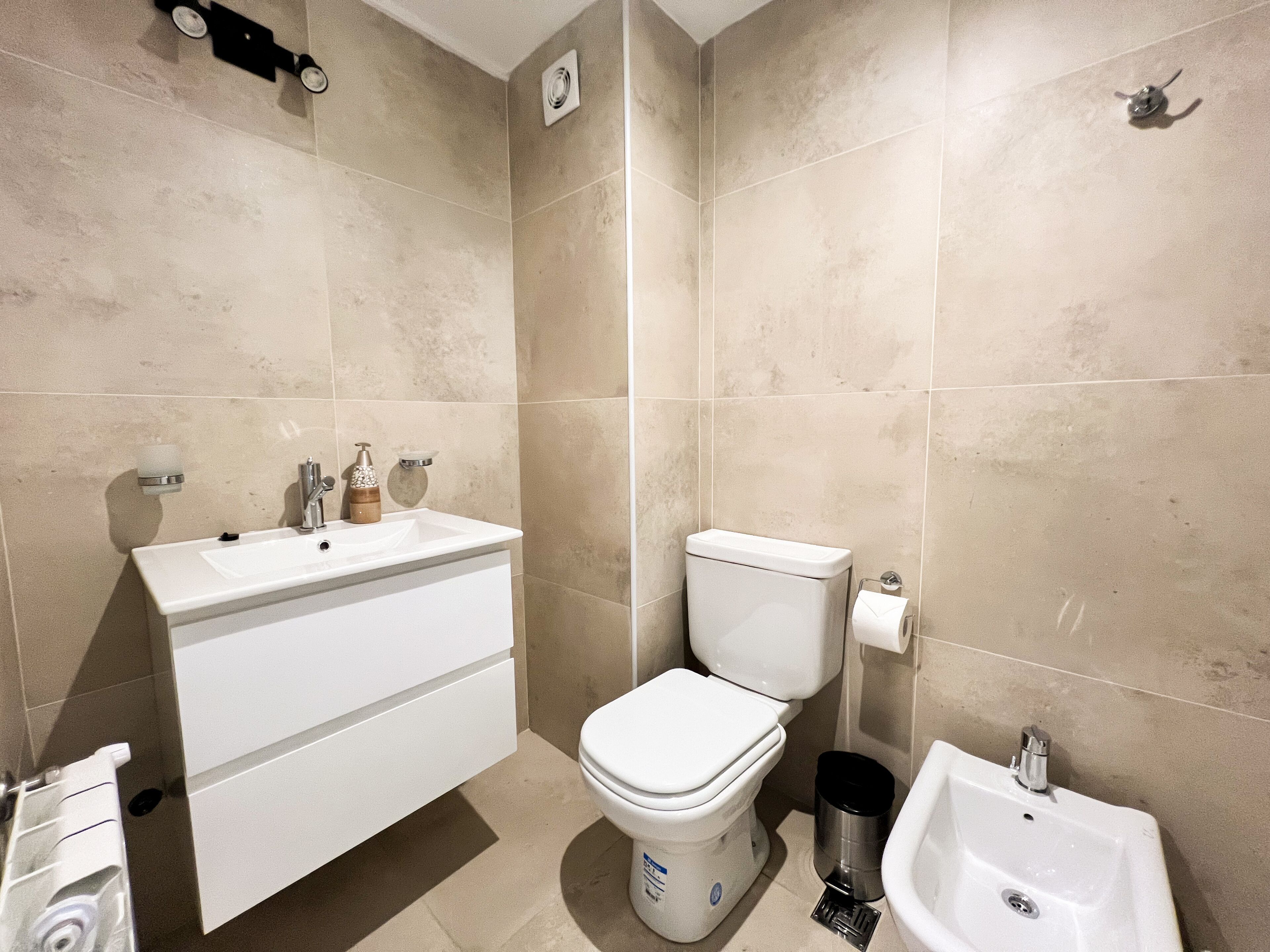 Un baño moderno con lavamanos, inodoro y bidé blancos.