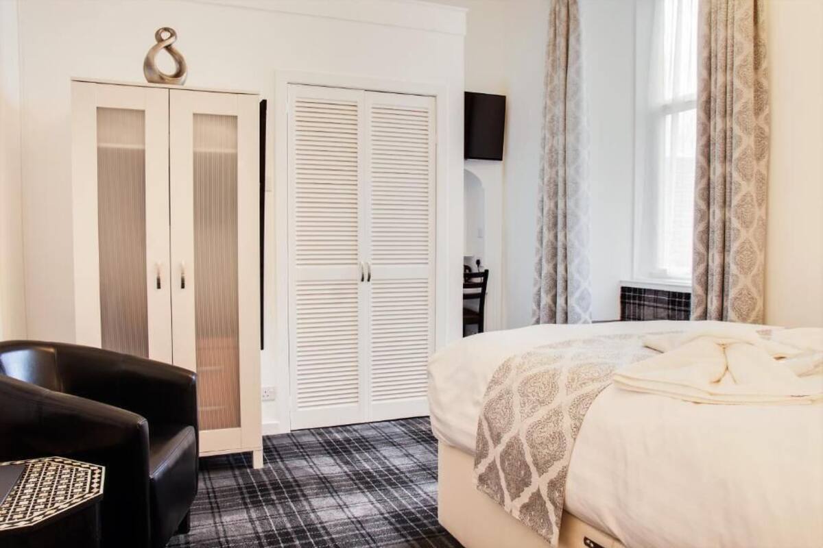 A hotel room with a bed, a wardrobe, a desk, and a chair.