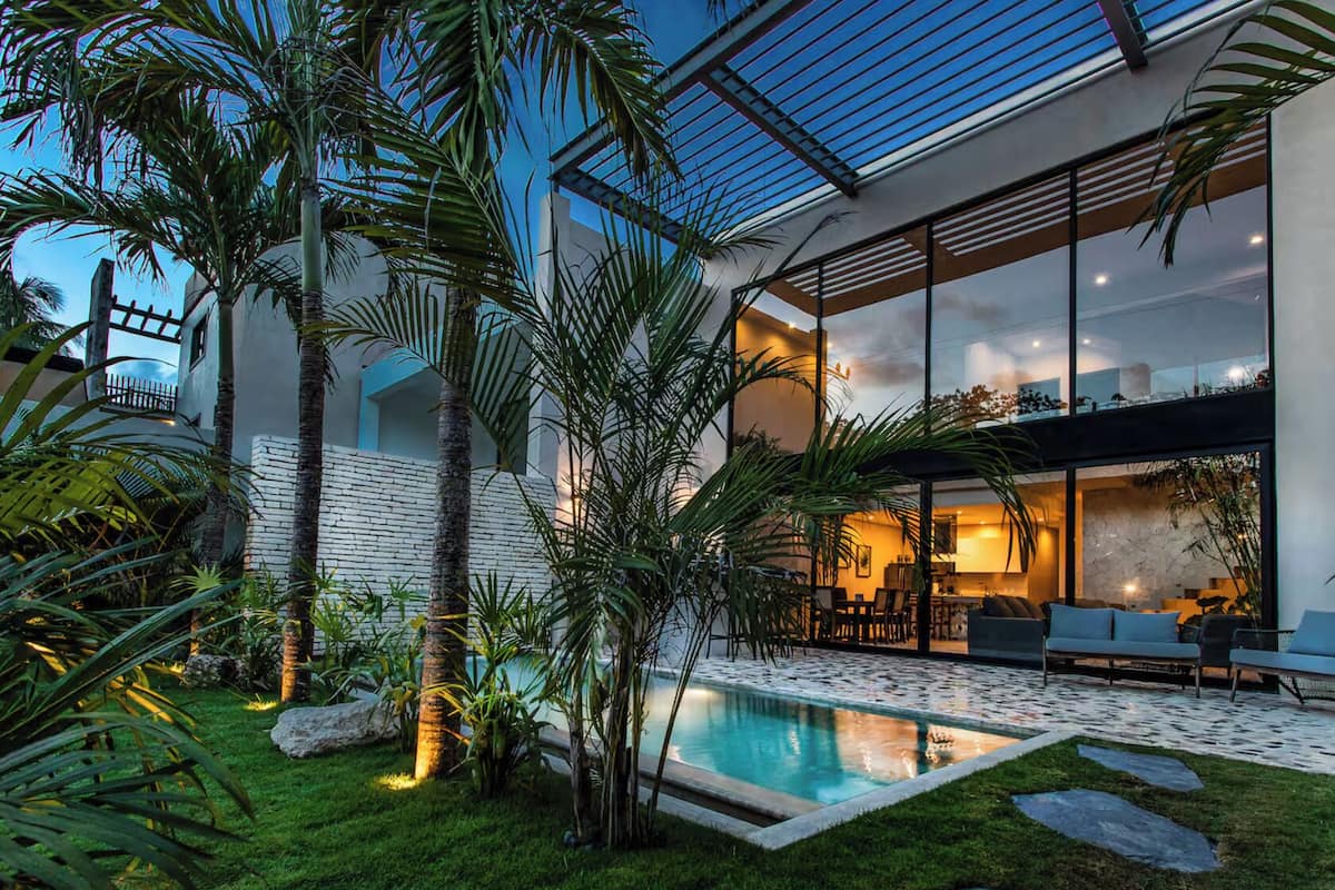 A modern house with a swimming pool, outdoor seating, and lush greenery.