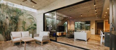 A spacious living area with a large glass door leading to a balcony, a ceiling fan, and a modern interior design.