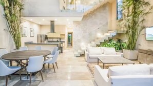 A modern interior with a dining area, sofas, and a staircase. - Hum Living Luxury Villas (Tulum)