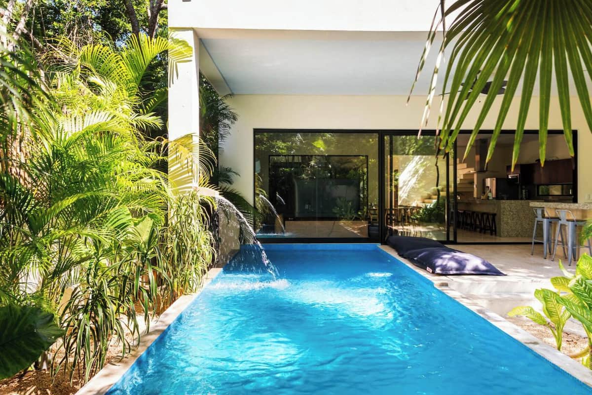 A modern outdoor pool area with a clear view of the adjacent kitchen and dining area.