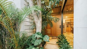 A modern building entrance with a stone pathway leading to a wooden door. - Hum Living Luxury Villas (Tulum)