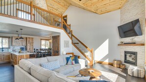 A spacious living area with a large sofa, a wooden staircase, and a kitchen in the background. - 'Meadowlark Mountain Club' w/ Views of the Rockies (Jefferson)