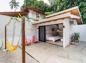Une maison moderne avec une chambre, un hamac et un fauteuil rose.