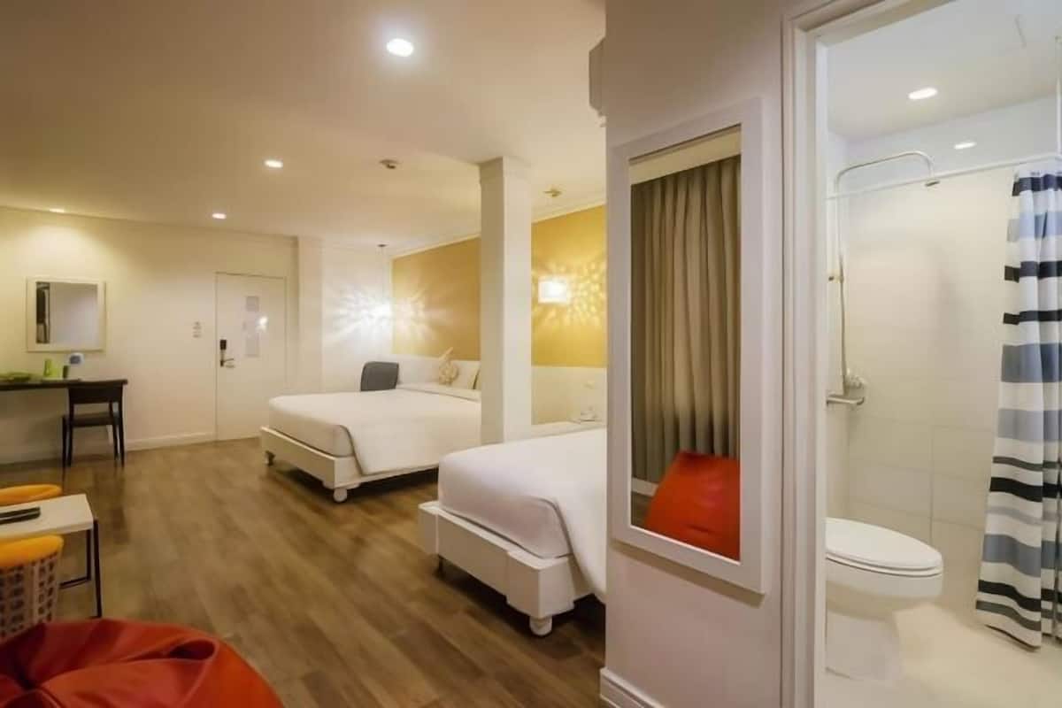 A hotel room with a bed, a desk, a chair, and a shower area.