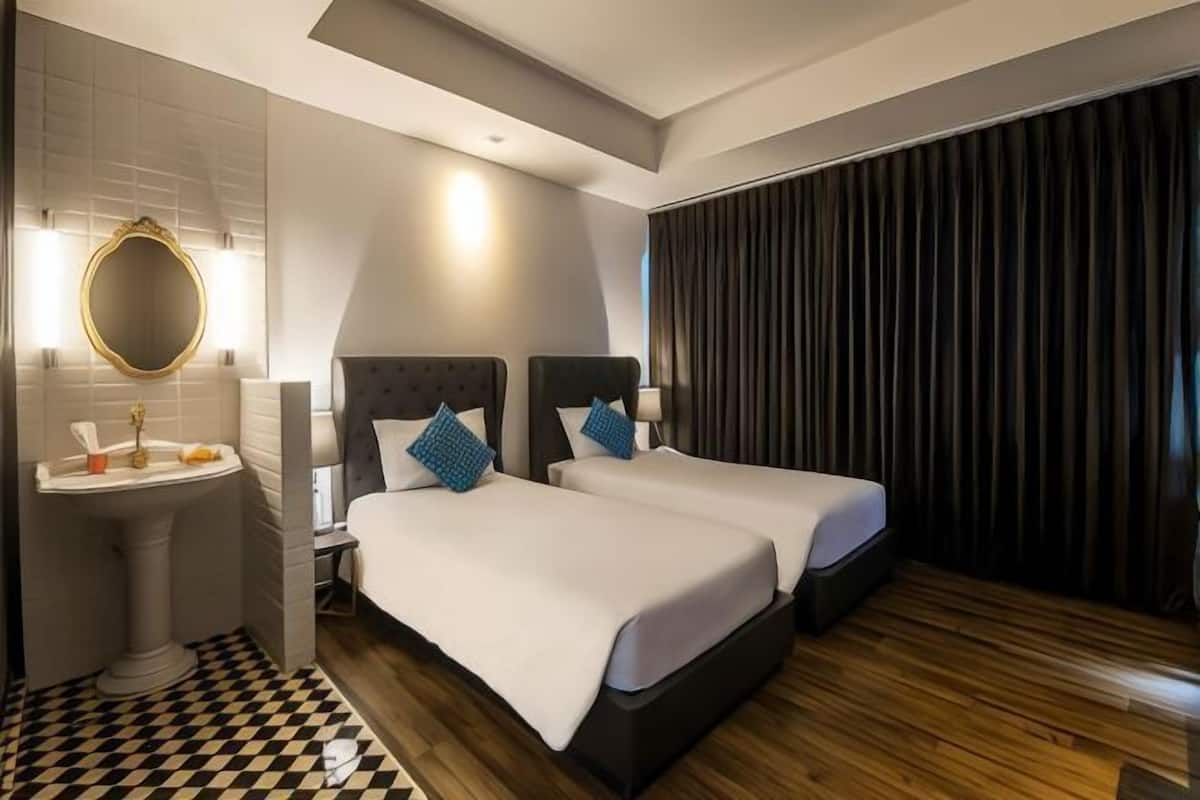 A hotel room with two beds, a large mirror, a sink, and a checkered floor.
