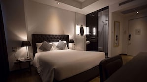 Una habitación de hotel moderna con una cama grande, lámparas de noche, un espejo y suelo de madera.