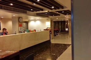 A hotel reception area with a reception desk, a clock, and a seating area. - First House Hotel Bangkok (Bangkok)