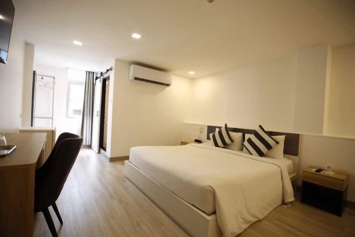A hotel room with a bed, bedside tables, a desk, and a chair.