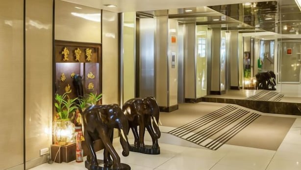 Un vestíbulo con una recepción, una pared con detalles decorativos dorados y tres estatuas de elefantes.
