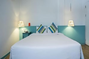 A bed with a white mattress, two bedside lamps, and two pillows with patterned designs. - First House Hotel Bangkok (Bangkok)