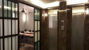 Un ascensor moderno con paredes de mármol y una mampara de vidrio.