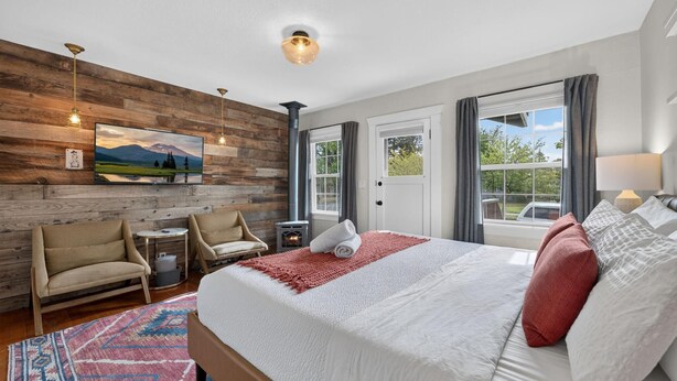 A bedroom with a bed, a fireplace, a sofa, a TV, and a window with curtains.