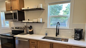 A modern kitchen with stainless steel appliances, wooden cabinets, and a window providing natural light.