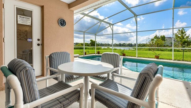 A covered outdoor area with a pool, chairs, and a table.