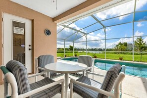 A covered outdoor area with a pool, chairs, and a table.