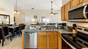 A modern kitchen with a dishwasher, microwave, stove, and wooden cabinets.
