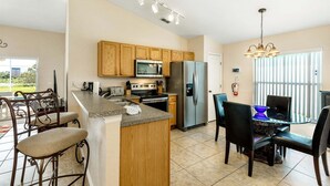 A kitchen with wooden cabinets, a stainless steel refrigerator, a microwave, and a gas stove.