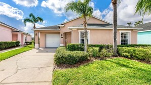 A single-story house with a garage, surrounded by well-maintained lawns and palm trees.