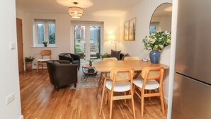 Une cuisine moderne dotée d’un grand réfrigérateur, d’une table à manger en bois et de chaises. Une fenêtre offre une vue sur l’extérieur.