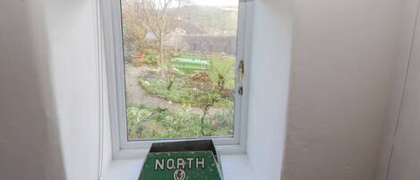 A window with a view of a garden and a sign reading "North of British".