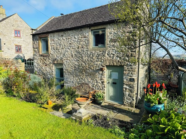 A stone house with a green door, a small window, and a sign reading "Tor Barn". - Tor Barn (Matlock)