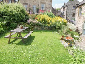 A garden with a wooden picnic table, a stone wall, and a variety of flowers. - Tor Barn (Matlock)